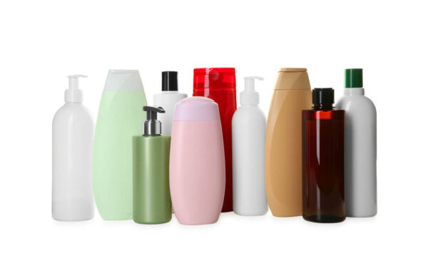 Diversas embalagens plásticas de shampoo coloridas e brancas, representando o uso de resinas recicladas de alta qualidade no setor de cosméticos e higiene.